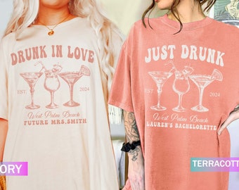 May include: Two t-shirts, one ivory, one terracotta, with cocktail designs. The ivory shirt says "DRUNK IN LOVE" with "West Palm Beach FUTURE MRS. SMITH" and "2024." The terracotta shirt reads "JUST DRUNK" with "West Palm Beach LAUREN'S BACHELORETTE" and "2024."