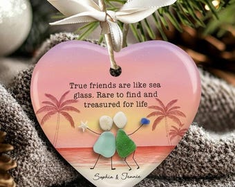 May include: Heart-shaped ceramic ornament with a beach scene and the text "True friends are like sea glass. Rare to find and treasured for life." Features two stick figures and the names "Sophia & Jennie."