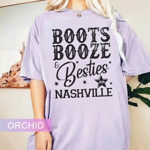 Może przedstawiać: Fioletowa koszulka z czarnym napisem "Boots, Booze & Besties Nashville 2024". Projekt zawiera gwiazdy i gwiazdę z rokiem 2024. Koszulka ma luźny kr&oacute;j.