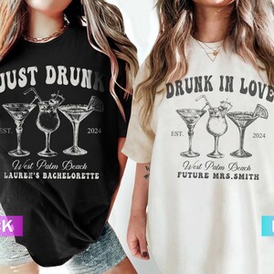 May include: Black and ivory t-shirts with cocktail graphics. The black shirt reads "JUST DRUNK" with "West Palm Beach LAUREN'S BACHELORETTE" and "EST. 2024". The ivory shirt says "DRUNK IN LOVE" with "West Palm Beach FUTURE MRS.SMITH" and "EST. 2024".