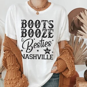 Może przedstawiać: Biała koszulka z napisem "Boots, Booze & Besties Nashville 2024" w czarnym kolorze. Koszulka ma okrągły dekolt i kr&oacute;tkie rękawy. Og&oacute;lny motyw to swobodny, zabawny styl.