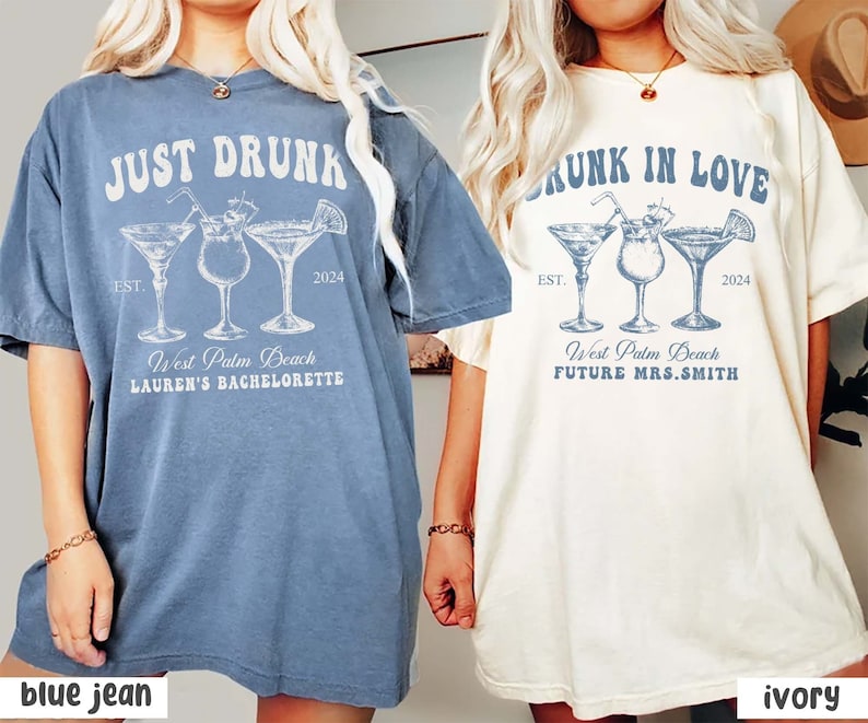 May include: Two oversized t-shirts, one blue jean and one ivory, featuring cocktail glass graphics. The blue shirt reads "JUST DRUNK" with "West Palm Beach" and "Lauren's Bachelorette" text. The ivory shirt says "DRUNK IN LOVE" with "West Palm Beach" and "FUTURE MRS.SMITH".