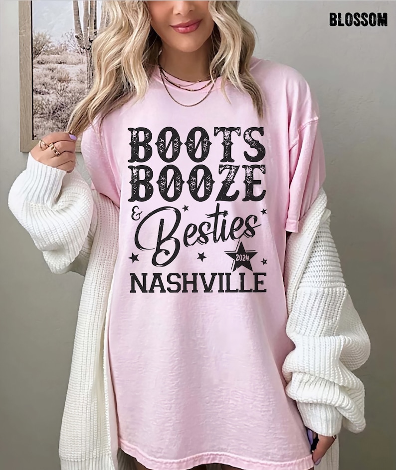Może przedstawiać: Jasnor&oacute;żowa koszulka z czarnym napisem "BOOTS BOOZE & Besties NASHVILLE 2024". Koszulka ma luźny kr&oacute;j i jest noszona przez osobę. Słowo "BLOSSOM" jest wydrukowane w prawym g&oacute;rnym rogu.