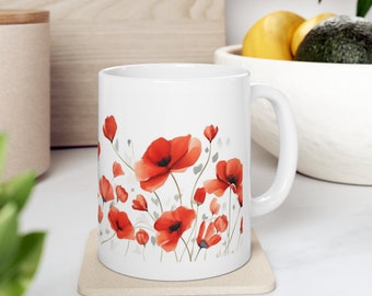May include: White ceramic mug featuring a watercolor design of red poppies with green stems and leaves. The floral pattern wraps around the mug, creating a vibrant and artistic look. The mug is on a beige coaster.