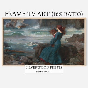 May include: A framed print of a painting depicting a woman in a blue dress standing on a rocky shore, looking out at a stormy sea. The woman has long red hair and is wearing a red sash. The sea is a dark blue and green, with white waves crashing against the rocks. The sky is a dark gray, with a few clouds. The painting is titled "The Lady of Shalott" by John William Waterhouse.
