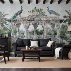 May include: A living room with a black leather sofa, white cushions, and a dark wood coffee table. The wall features a mural of an ornate structure with peacocks, set in a tropical landscape. The room includes a black armchair and a beige rug.