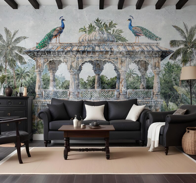 May include: A living room with a black leather sofa, white cushions, and a dark wood coffee table. The wall features a mural of an ornate structure with peacocks, set in a tropical landscape. The room includes a black armchair and a beige rug.