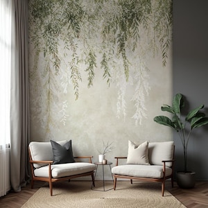 May include: A serene interior scene featuring two armchairs with light-colored upholstery and wooden frames. A small side table sits between them. The backdrop is a wall mural with a botanical design of hanging green and white leaves, creating a calming atmosphere.
