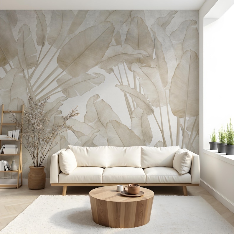 May include: A modern living room featuring a white sofa, a round wooden coffee table, and a large beige leaf-patterned wallpaper. A wooden ladder shelf and a potted plant add to the room's decor. The room has a bright, airy feel.
