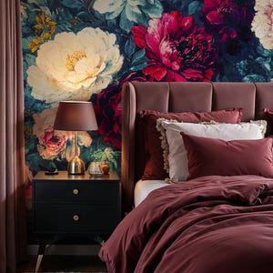 May include: A bedroom scene featuring a floral wallpaper with large white and red flowers. A burgundy bed with matching bedding and pillows is on the right. A black nightstand with a gold lamp and a small rug complete the scene.