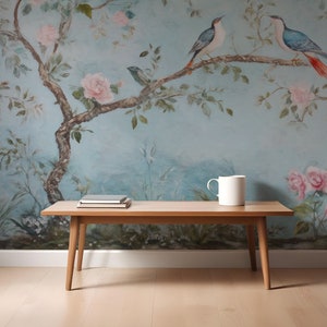 May include: A wooden coffee table with a light wood finish. The table has a rectangular top and four legs. The table is in front of a wall with a blue and white floral wallpaper featuring birds.