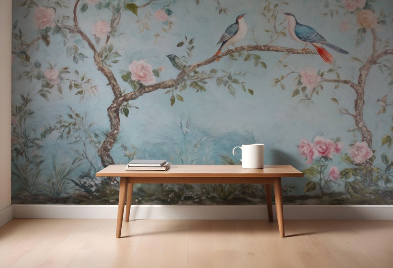 May include: A wooden coffee table with a light wood finish. The table has a rectangular top and four legs. The table is in front of a wall with a blue and white floral wallpaper featuring birds.