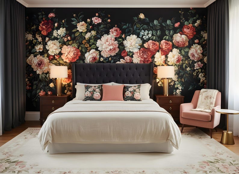 May include: A bedroom with a floral wallpaper backdrop featuring large pink, red, and white flowers. A bed with a tufted headboard, white bedding, and decorative pillows is centered. Two bedside tables with lamps flank the bed. A pink armchair and a rug complete the scene.