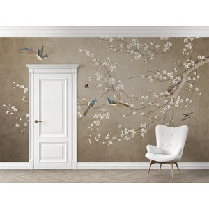 May include: A beige wall mural with a white floral design and blue birds. The mural is in a room with a white door and a white chair.