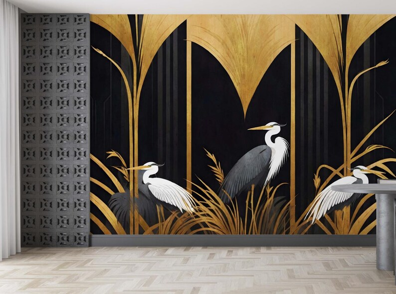 May include: A decorative wall mural featuring three herons in a stylized art deco design. The background is black with gold accents and vertical lines. The herons are depicted in shades of gray and white, with long beaks and elegant poses. The mural is a striking piece of wall art.