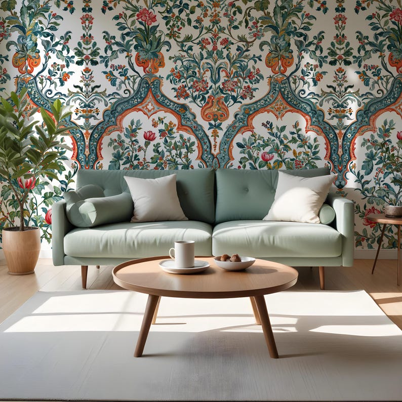 Op de afbeelding: Een woonkamer met een lichtgroene bank, witte kussens en een ronde houten salontafel. Het behang heeft een bloemenpatroon. Een plantenpot en een wit tapijt zijn ook aanwezig. De kamer is gevuld met natuurlijk licht.