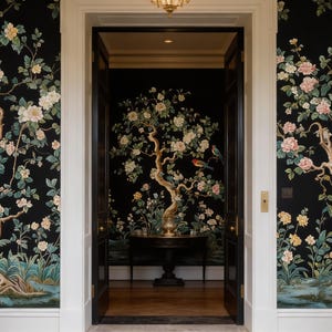 May include: A doorway framed by black wallpaper featuring a floral and bird design. The wallpaper showcases flowering trees with pink, yellow, and white blossoms, and colorful birds. The doorway leads to a room with similar wallpaper and a round table.