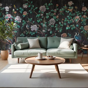 May include: A mint green sofa with two white cushions and a round wooden coffee table. The background features dark floral wallpaper with roses, birds, and foliage. A white rug and a potted plant complete the living room scene.