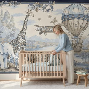 Pode incluir: Cena de ber&ccedil;&aacute;rio com um ber&ccedil;o de madeira clara e um colch&atilde;o azul. O fundo &eacute; um mural com uma paisagem azul e branca, incluindo uma girafa, um elefante, um bal&atilde;o de ar quente e um avi&atilde;o. Uma mulher est&aacute; em p&eacute; ao lado do ber&ccedil;o.