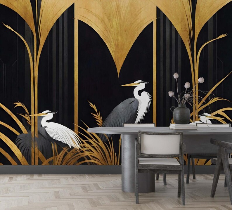 May include: A black and gold art deco style mural featuring two herons with white and gray feathers. The background is black with gold stylized plants and geometric shapes. A gray table and chairs are in the foreground.