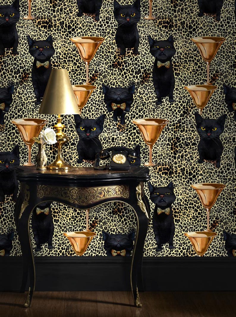 May include: Black cats with bow ties are featured on a gold and black leopard print wallpaper. A gold lamp sits on a black table with a gold trim. A black rotary phone is on the table.