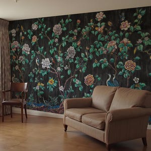May include: A room with a dark floral wallpaper featuring roses, birds, and foliage. A brown leather sofa and a wooden chair are positioned in front of the wallpaper. The room has wooden flooring and curtains.