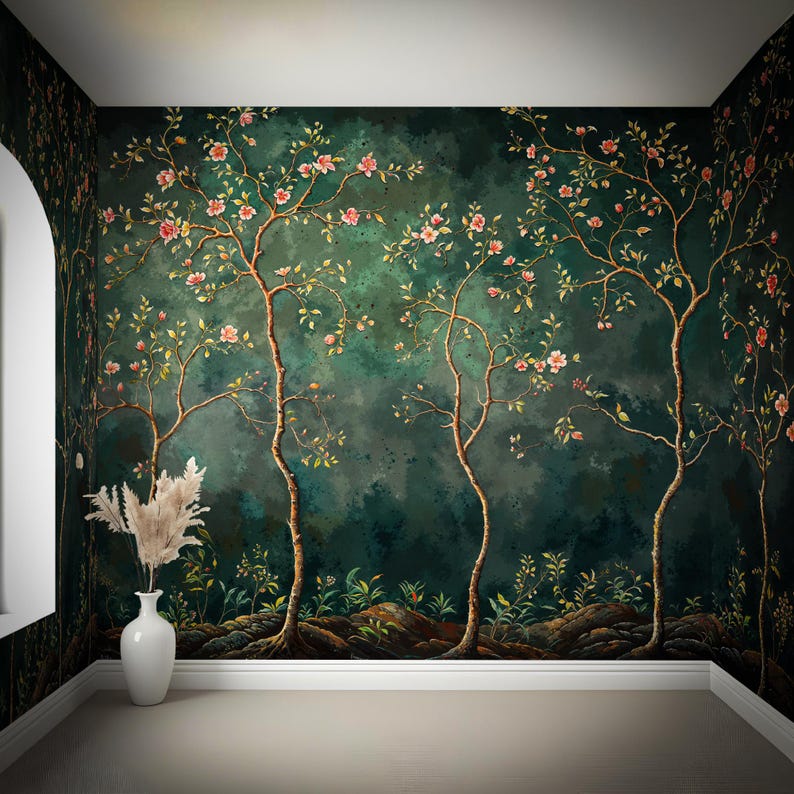 Op de afbeelding: Een kamer met donkergroen bloemenbehang met gestileerde bomen met roze bloesems. Een witte vaas met gedroogd pampasgras staat in de hoek. De kamer heeft een lichtgekleurde vloer en een witte lijst.