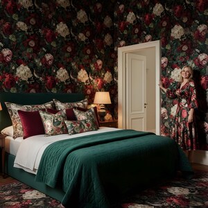 May include: A bedroom with a dark green bed, a matching quilt, and floral patterned pillows. The walls are covered in a dark floral wallpaper. A woman in a floral dress stands in the doorway.