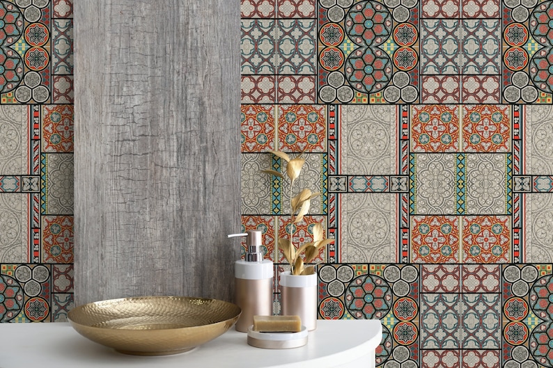 May include: A bathroom with a gray wood-look wall and a patterned tile backsplash. The backsplash features a variety of geometric designs in shades of red, blue, green, and yellow. A gold metal bowl sits on a white countertop in front of the backsplash. Two gold soap dispensers and a bar of soap are also on the countertop.