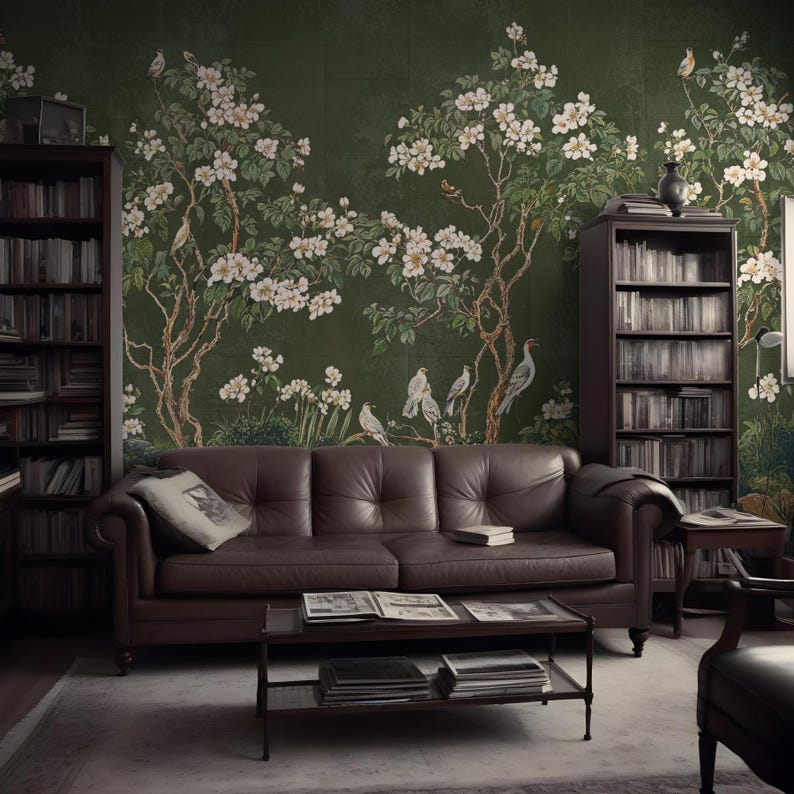 May include: A dark green wallpaper with a floral design featuring white flowers and birds. The wallpaper is in a living room with a brown leather sofa, a coffee table, and bookshelves.