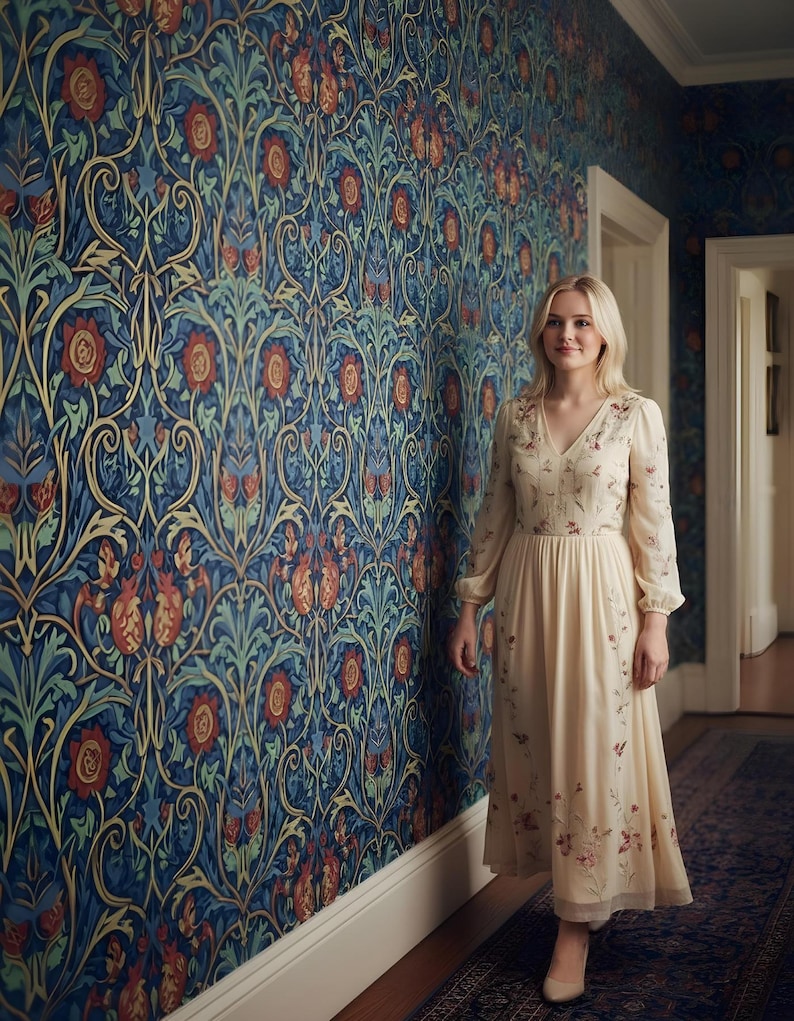 May include: A woman in a cream-colored dress with floral embroidery stands in a hallway. The dress has long sleeves and a V-neck. The wall behind her is covered in a blue floral wallpaper with red and green accents. A patterned rug is on the floor.