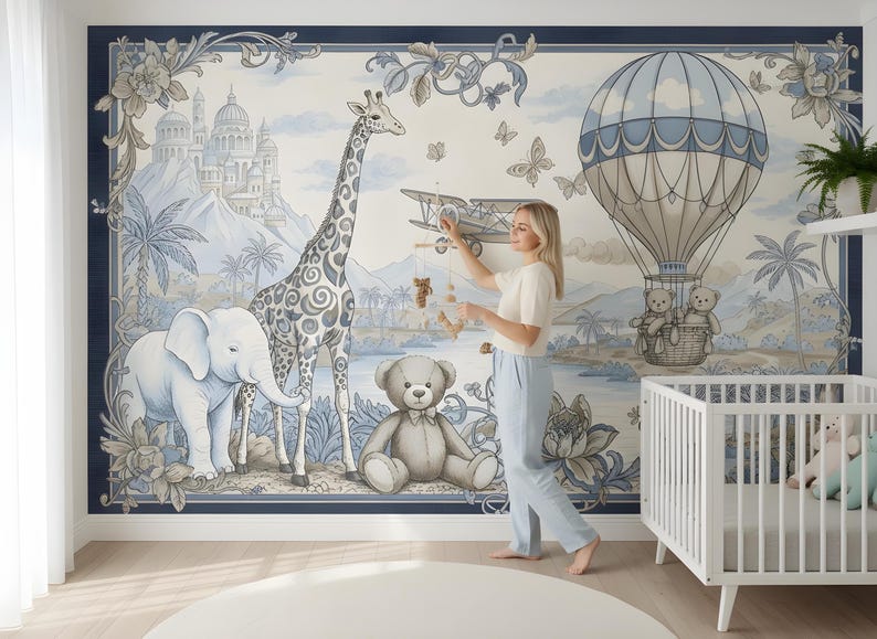 Pode incluir: Um mural de parede de ber&ccedil;&aacute;rio com um design caprichoso com uma girafa, um elefante, um ursinho de pel&uacute;cia e um bal&atilde;o de ar quente. O mural tem um esquema de cores azul e branco com uma borda decorativa e um ber&ccedil;o no canto.