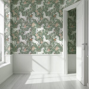 May include: A room with walls covered in a green floral wallpaper featuring white unicorns. The wallpaper is paired with white wainscoting and a white door frame. The room has a white floor and a window on the left side.