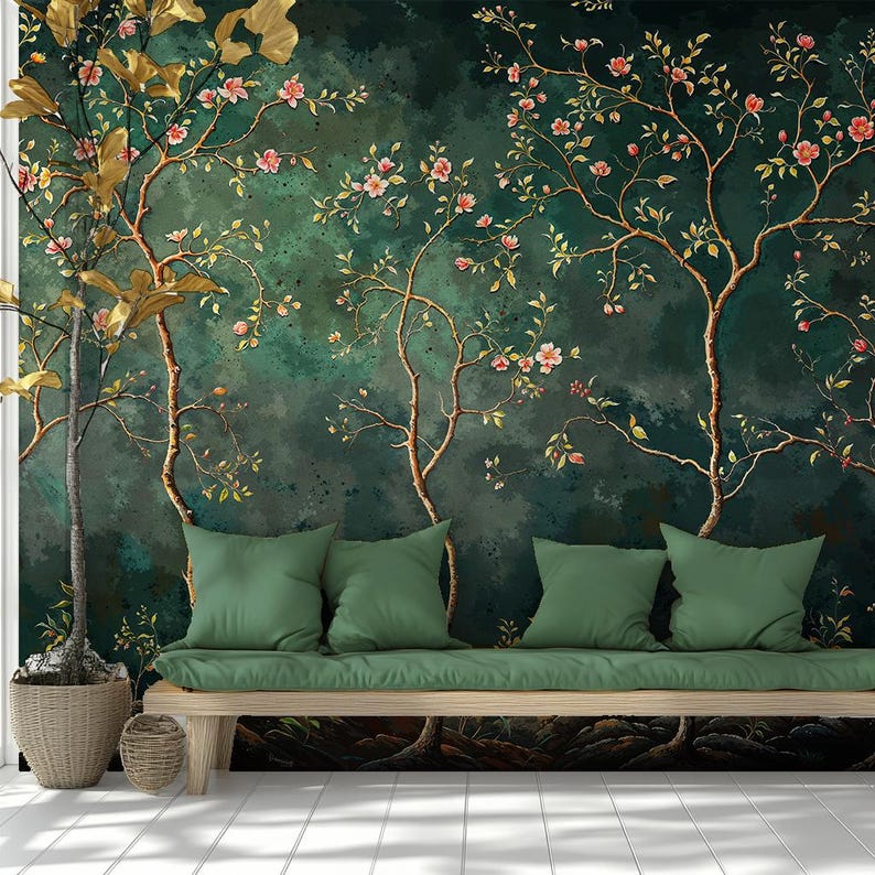 Op de afbeelding: Een donkergroene muurschildering met gouden en bruine boomtakken, roze bloemen en groene bladeren. Een houten bank met groene kussens en kussens staat voor de muurschildering. Een potplant staat links.