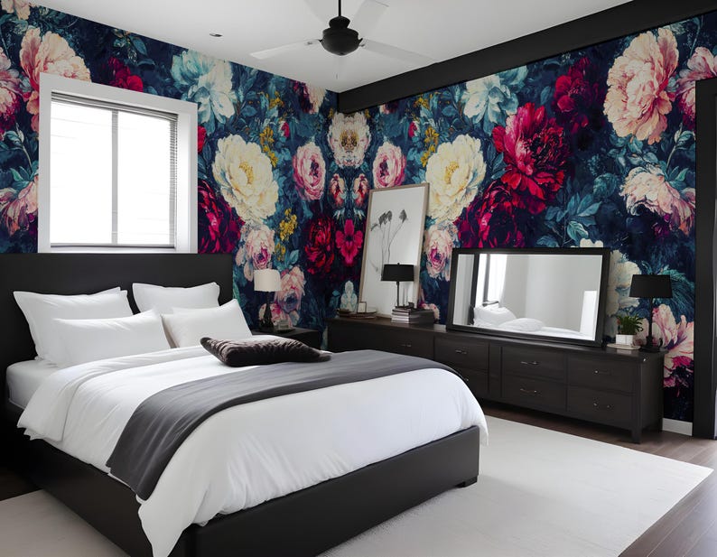May include: A bedroom with a floral wallpaper in shades of pink, white, and dark blue. The room features a black bed frame with white bedding, a dark dresser, a large mirror, and a white rug.