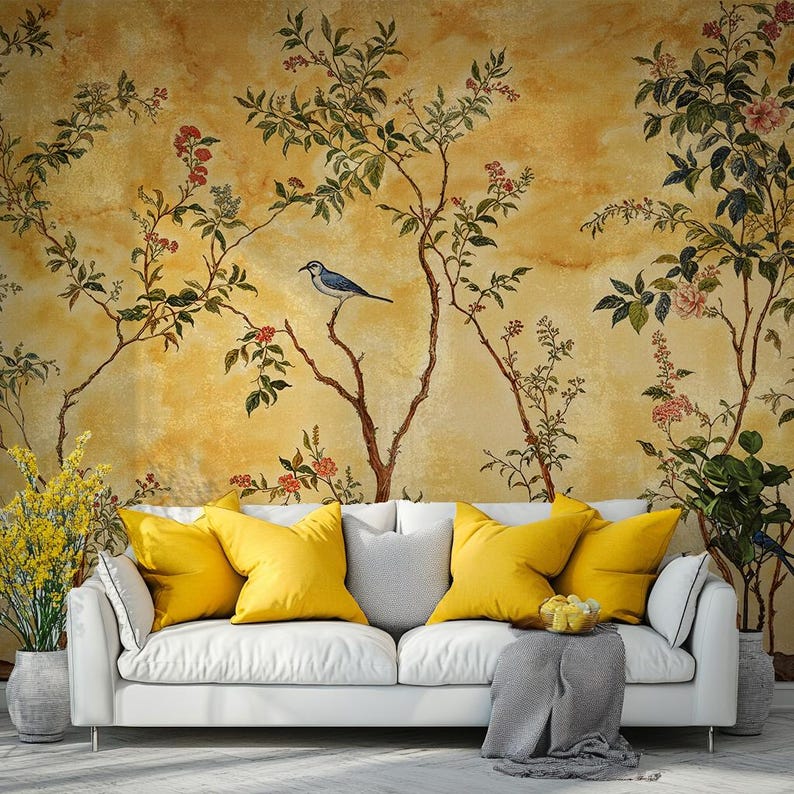 May include: A white sofa with yellow throw cushions sits in front of a wall mural featuring a yellow background with a stylised floral design and a blue bird perched on a branch.