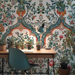 Op de afbeelding: Een thuiskantoor met een houten bureau, een turquoise stoel en een turquoise bureaulamp. Het bureau heeft potplanten en een laptop. De achtergrond is bloemenbehang met een witte basis en ingewikkelde patronen in turquoise, oranje en groen.