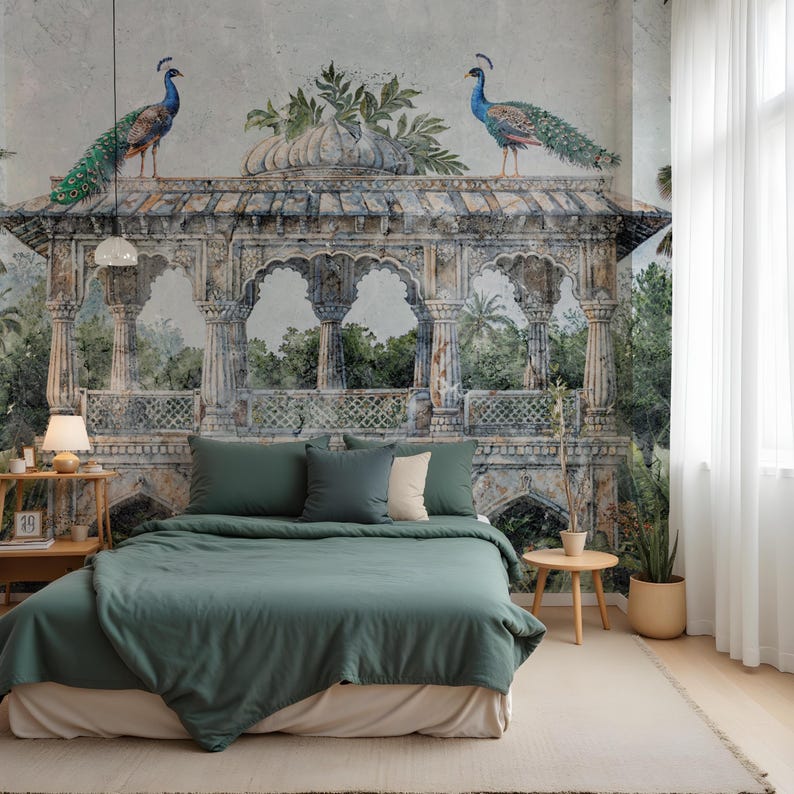 May include: A bedroom scene featuring a green bedspread and pillows, set against a detailed wall mural. The mural shows an ornate structure with two peacocks. A side table, lamp, and a potted plant complete the room's decor.
