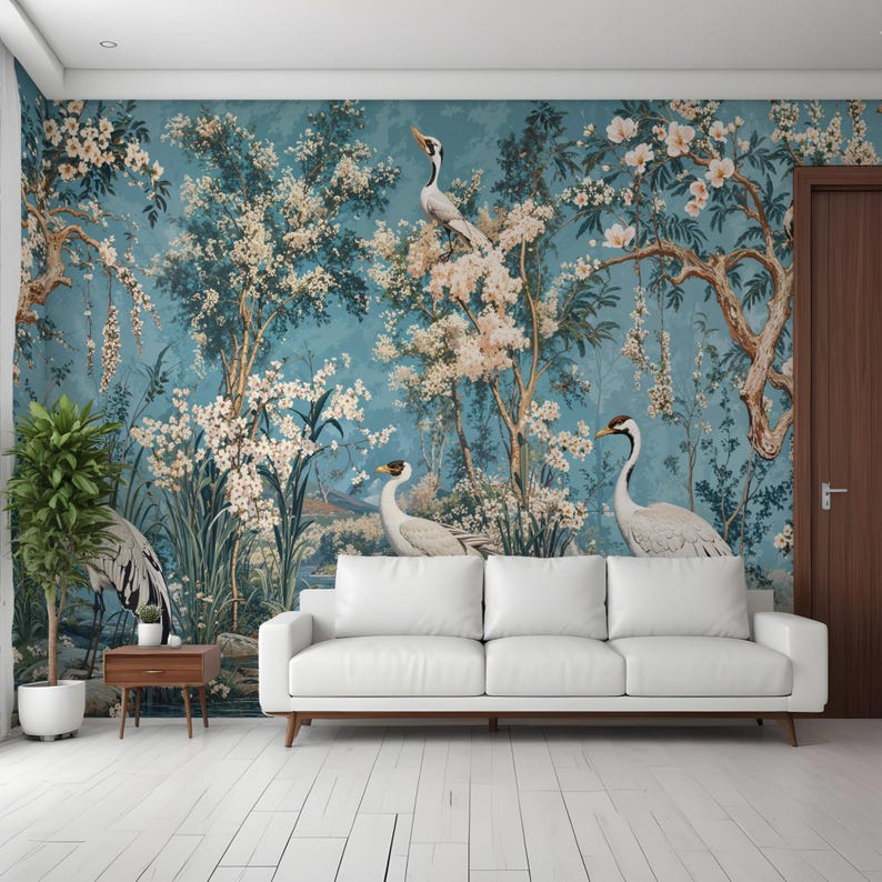 Op de afbeelding: Een witte bank staat voor een muurschildering met een blauwe achtergrond, witte bloemen en witte vogels. De muurschildering toont een serene en rustige sc&egrave;ne.