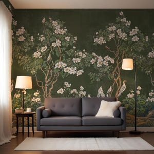 May include: A dark gray sofa with a white throw pillow sits in front of a green floral wallpaper with white flowers and birds. Two lamps with white shades are on either side of the sofa.