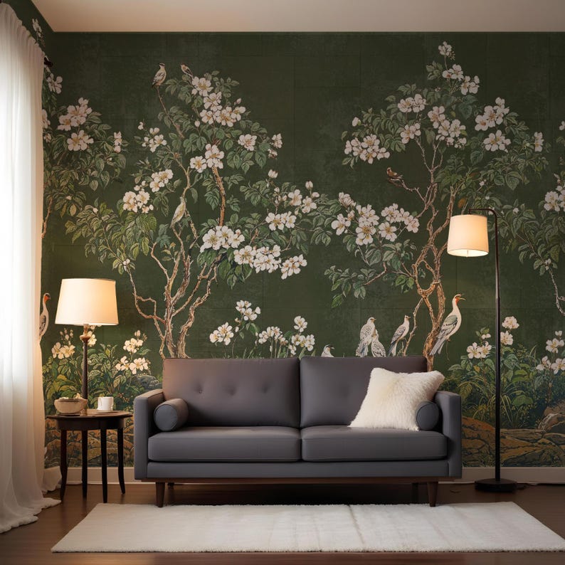 May include: A dark gray sofa with a white throw pillow sits in front of a green floral wallpaper with white flowers and birds. Two lamps with white shades are on either side of the sofa.