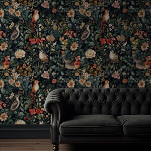 K&ouml;nnte beinhalten: Ein schwarzes Samtsofa steht vor einer dunkelblauen Tapete mit einem floralen Muster aus bunten Blumen, V&ouml;geln und Bl&auml;ttern.