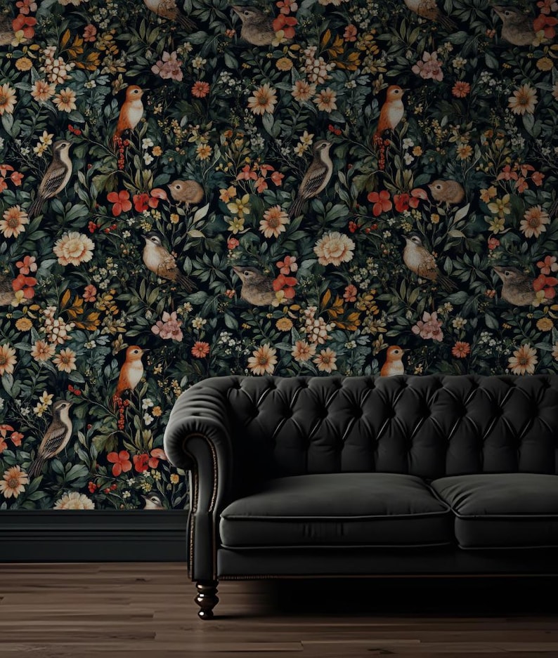 K&ouml;nnte beinhalten: Ein schwarzes Samtsofa steht vor einer dunkelblauen Tapete mit einem floralen Muster aus bunten Blumen, V&ouml;geln und Bl&auml;ttern.