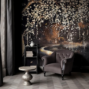 May include: A room with a dark floral mural featuring a tree with white blossoms. A gray velvet armchair, a small silver table, and a black metal shelf with books and a vase are in front of the mural. The floor has a gray and white herringbone pattern.