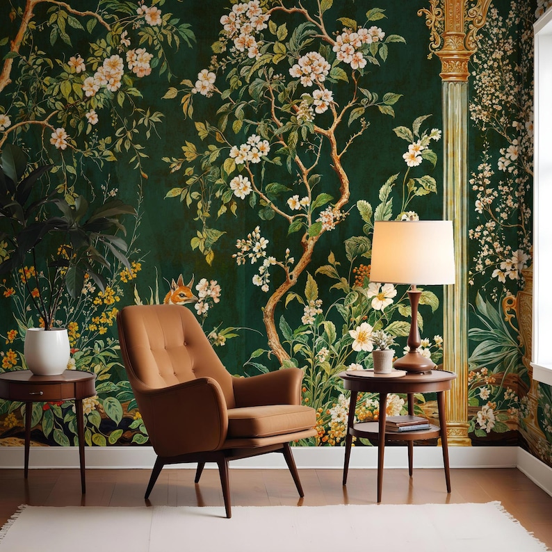 May include: A brown armchair with a green floral wallpaper backdrop. The wallpaper features white flowers and a small fox. A brown side table with a lamp and a book sits next to the chair.