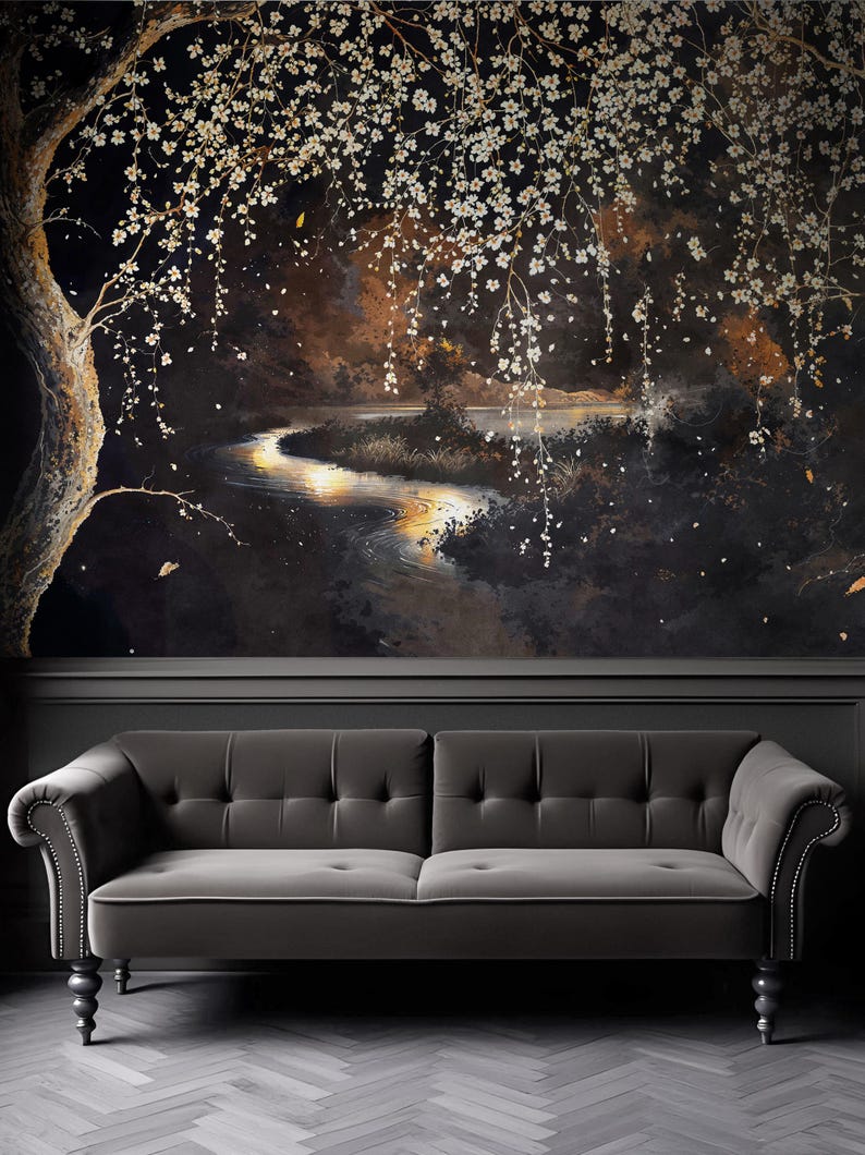 May include: A dark, moody mural depicting a serene landscape with a winding river reflecting golden light. White blossoms cascade from a tree, creating a dreamy, ethereal atmosphere. A gray tufted sofa sits below the mural.