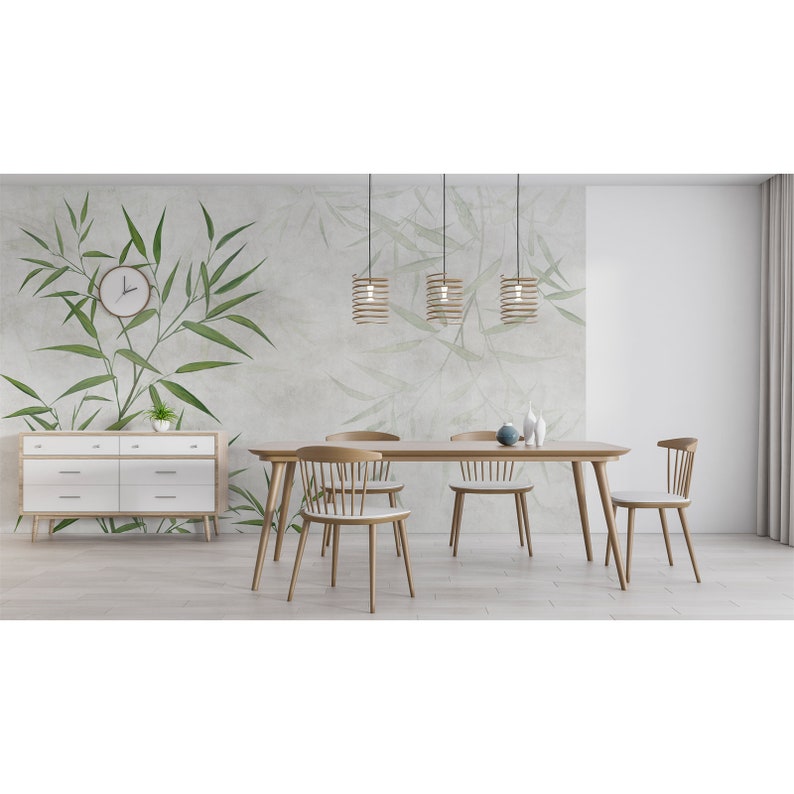 Op de afbeelding: Een lichte houten eettafel met vier stoelen en drie hanglampen. De muur achter de tafel heeft een groen-witte bamboe behang.