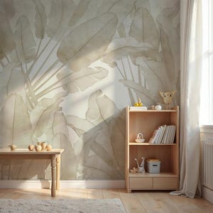May include: A room with a large, neutral-toned banana leaf wallpaper. A light wood bookshelf and small table are in the room. The table has several small wooden decorative objects. A rug and curtain are also visible.