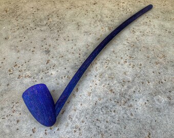 May include: A long, blue wooden pipe with a curved bowl. The pipe is made of a dark wood with a blue stain and has a natural grain pattern.