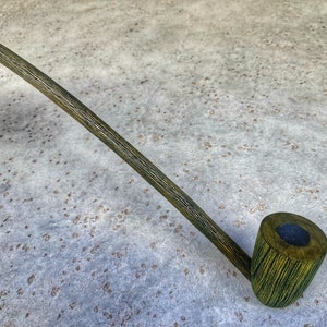 May include: A long, green wooden pipe with a curved stem and a bowl with a black interior.